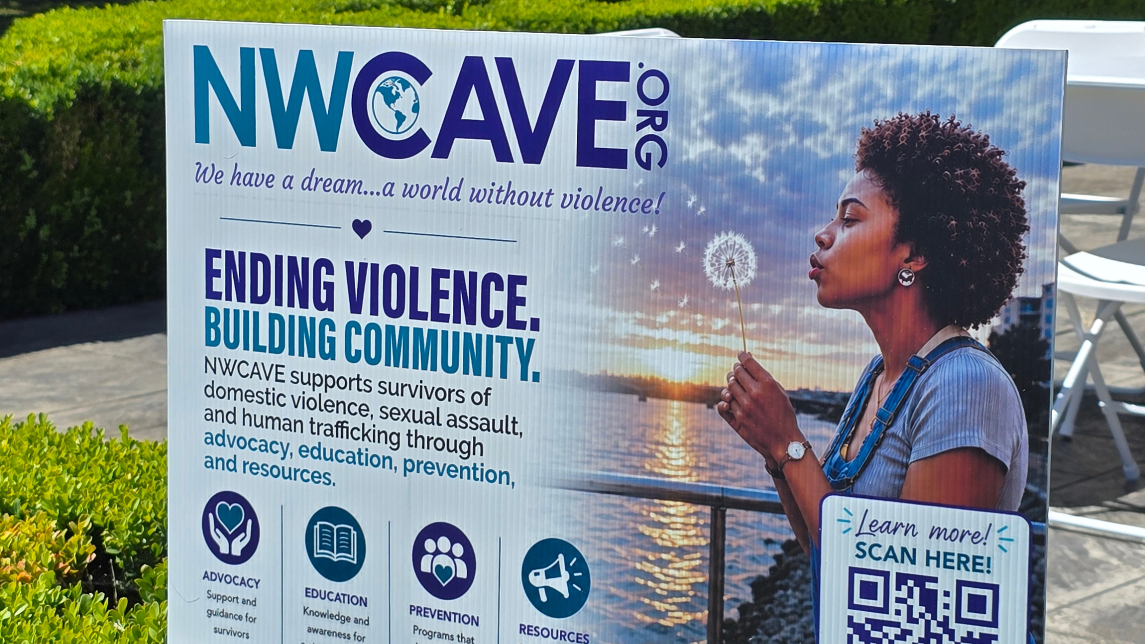 NWCAVE.ORG signage reading Ending Violence, Building Community at a community event